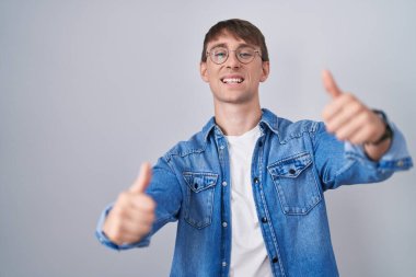 Beyaz, sarışın, gözlüklü, elinde olumlu bir jest yapan, gülümseyen ve başarı için mutlu bir adam. kazanan jest. 