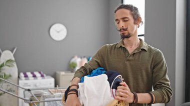 Çamaşır odasında elinde sepet tutan İspanyol genç adam.