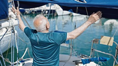 Yaşlı gri saçlı adam teknede ters duruyor.