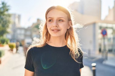 Young blonde woman smiling confident looking to the side at street
