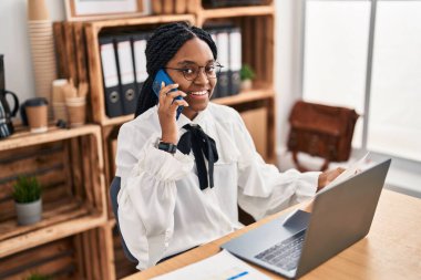 Afrika kökenli Amerikalı kadın iş adamı ofisteki akıllı telefon okuma belgesiyle konuşuyor.
