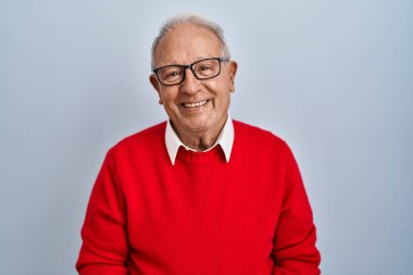 İzole edilmiş arka planda gri saçlı yaşlı bir adam ellerini kavuşturup gülümseyerek gevşemiş ve neşeliydi. Başarı ve iyimserlik 