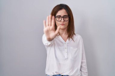 Esmer kadın, izole edilmiş beyaz arka planda durup avuç içiyle şarkı söylemeyi kesiyor. Yüzünde olumsuz ve ciddi bir jest olan uyarı ifadesi. 