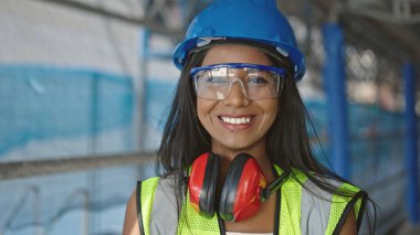 Afro-Amerikalı kadın inşaatçı gülümseyerek sokakta duruyor.