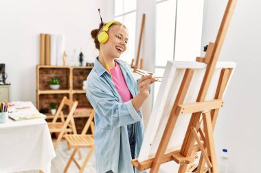 Sanat stüdyosunda müzik dinleyen genç beyaz kadın sanatçı.