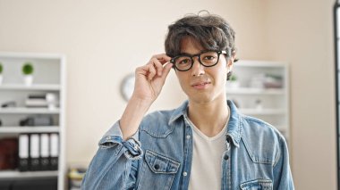 Genç İspanyol iş adamı ofiste kendinden emin gülümsüyor.