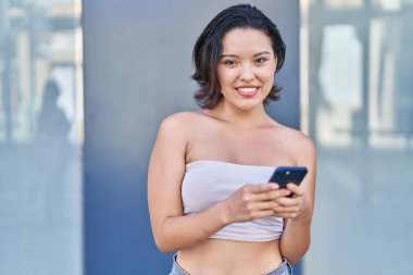 Sokakta akıllı telefon kullanan, kendine güvenen genç İspanyol kadın.