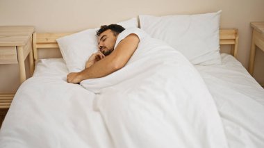 Genç İspanyol adam yatakta uzanıp yatak odasında uyuyor.