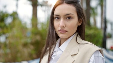 Parkta ciddi bir ifadeyle duran genç, güzel İspanyol kadın.