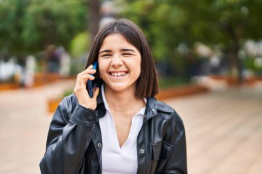 Genç, güzel İspanyol kadın gülümsüyor. Parktaki akıllı telefondan konuşuyor.