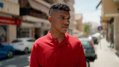 Sokakta rahat bir ifadeyle yan tarafa bakan genç latin adam.