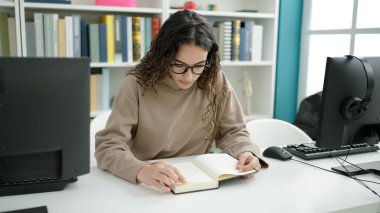 Kütüphane üniversitesinde kitap okuyan güzel İspanyol bir kadın öğrenci.