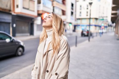 Caddede mutsuz bir ifadeyle duran genç sarışın kadın.