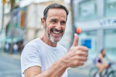 Orta yaşlı adam gülümsüyor. Kendine güveniyor. Başparmağıyla caddede imza atıyor.