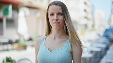 Sokakta ciddi bir ifadeyle duran genç sarışın kadın.