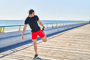 Young man stretching legs at seaside