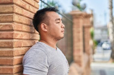 Young chinese man looking to the side with serious expression at street