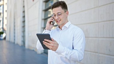 Genç İspanyol adam hastanede dokunmatik ped kullanarak akıllı telefondan konuşuyor.