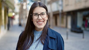 Sokakta kendinden emin gülümseyen genç İspanyol kadın.