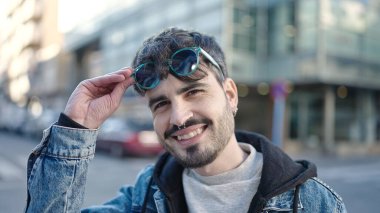 Young hispanic man smiling confident wearing sunglasses at street