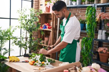 Genç Arap çiçekçi çiçekçi çiçekçide buket çiçek yapar.