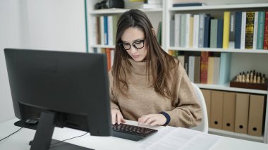 Güzel İspanyol kadın öğrenci kütüphane üniversitesinde bilgisayar kullanıyor.