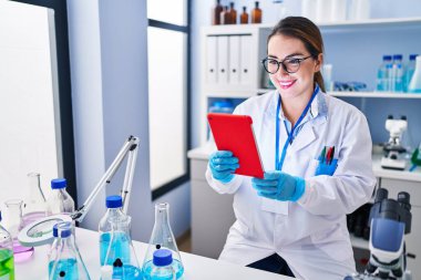 Genç ve güzel İspanyol bilim kadını. Laboratuvarda dokunmatik ped kullanarak gülümsüyor.