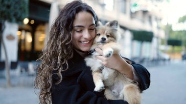 Köpeğiyle gülümseyen, sokakta kendine güvenen genç İspanyol kadın.