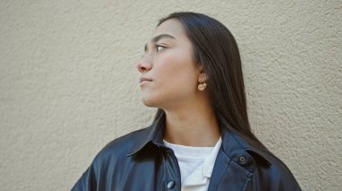 Genç, güzel İspanyol kadın, izole edilmiş beyaz arka planda ciddi bir ifadeyle yan tarafa bakıyor.