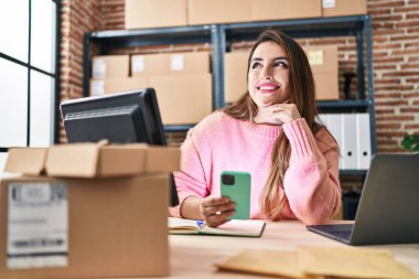 Genç, güzel, İspanyol bir kadın. İş kadını. Ofiste akıllı telefon kullanıyor.