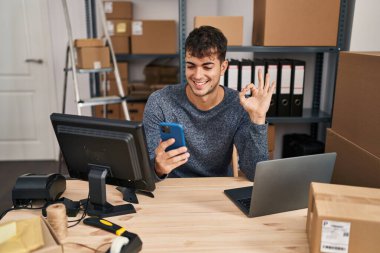 Küçük işletmelerde çalışan İspanyol genç adam akıllı telefon kullanıyor. Gülümsüyor, gülümsüyor. Tamam. Elle gözün içine bak. 