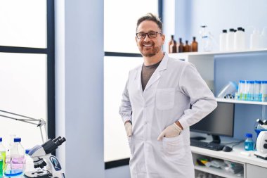 Laboratuvarda kendine güvenen genç beyaz bilim adamı gülümsüyor.