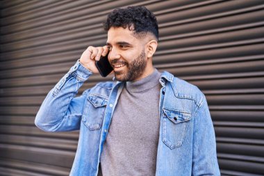 Genç İspanyol adam gülümsüyor. Kendine güveniyor. Sokakta akıllı telefondan konuşuyor.