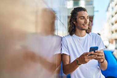 Sokakta akıllı telefon kullanan, kendine güvenen genç bir İspanyol.