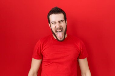 Gündelik kırmızı tişört giyen genç İspanyol adam komik bir ifadeyle dilini dışarı çıkarıyor. duygu kavramı. 