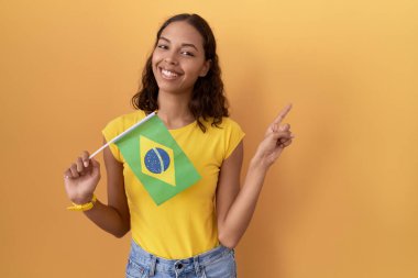 Elinde Brezilya bayrağı olan genç bir İspanyol kadın yüzünde kocaman bir gülümsemeyle kameraya el ile işaret ediyor.. 