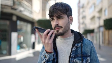 Genç İspanyol adam sokakta akıllı telefonuyla sesli mesaj yolluyor.