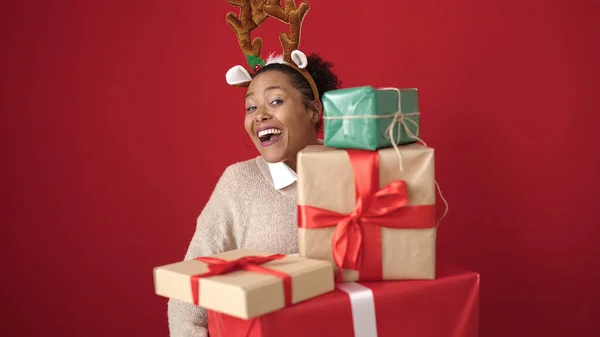 Afroamerikanerin Mit Weihnachtsgeschenken Trägt Rentierohren Über Isoliertem Rotem Hintergrund — Stockfoto