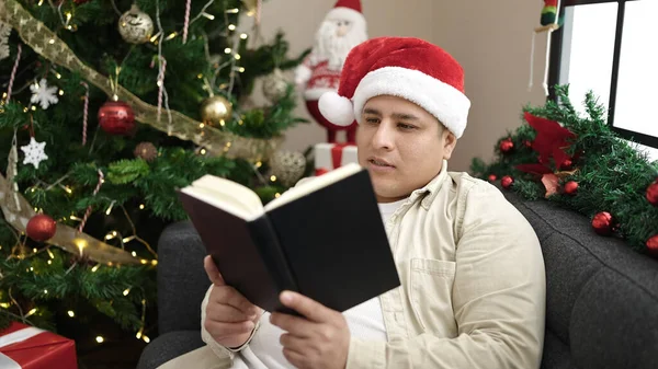 Mladý Hispánec Muž Čtení Knihy Slaví Vánoce Doma — Stock fotografie
