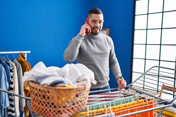 Young Latin Man Talking Smartphone Hanging Clothes Clothesline Laundry Room — Fotografia de Stock