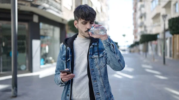 Genç Spanyol Adam Içmek Için Caddede Akıllı Telefon Kullanıyor — Stok fotoğraf