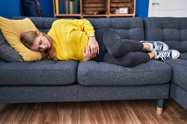 Young Blonde Woman Suffering Menstrual Pain Lying Sofa Home — Fotografia de Stock
