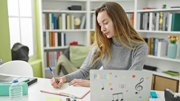 在图书馆大学 年轻的高加索女学生在笔记本上使用笔记本电脑写作 — 图库照片