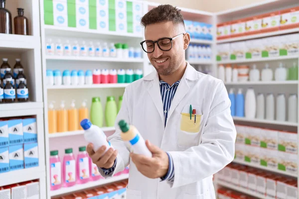 Fiatal Spanyol Férfi Gyógyszerész Mosolyog Magabiztos Gazdaság Gyógyszeres Üvegek Gyógyszertárban — Stock Fotó