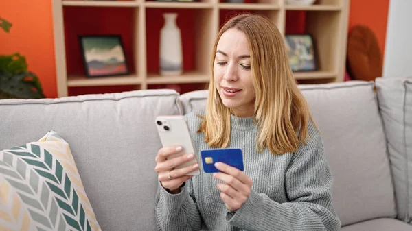 Jonge Blonde Vrouw Winkelen Met Smartphone Creditcard Zitten Bank Thuis — Stockfoto