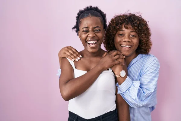 两个非洲女人站在粉红的背景上笑着 笑得很大声 因为有一个可笑的疯狂笑话 — 图库照片