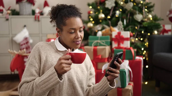 Africano Americano Mulher Usando Smartphone Beber Café Sentado Árvore Natal — Fotografia de Stock