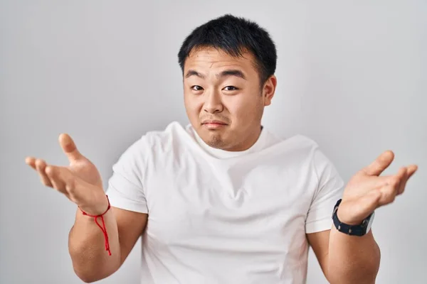 Молодой Китаец Стоящий Белом Фоне Невежественный Смущенный Поднятыми Руками Руками — стоковое фото