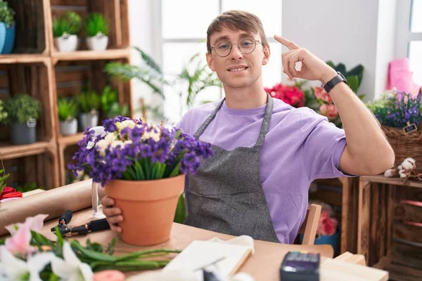 白人ブロンド男仕事で花屋の店笑顔を指して頭に1本の指 素晴らしいアイデアや考え 良い記憶 — ストック写真
