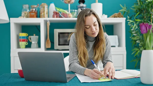 食堂でノートパソコンを使ってノートを書く若い白人女性学生 — ストック写真